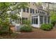 Two-story home with a sunroom, showcasing yellow siding, black shutters, brick patio, and established greenery at 1208 College Pl, Raleigh, NC 27605