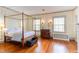 Spacious bedroom with wood floors, a four poster bed, period dresser, and updated lighting at 1208 College Pl, Raleigh, NC 27605