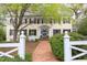 Charming two-story home with yellow siding, black shutters, brick walkway, and a white picket fence at 1208 College Pl, Raleigh, NC 27605