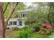 A view of the two-story house through lush trees and greenery, highlighting its yellow siding and black shutters at 1208 College Pl, Raleigh, NC 27605
