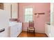 Laundry room with a washer, dryer, utility sink, hardwood floors, and pink walls at 1208 College Pl, Raleigh, NC 27605