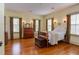 Large primary bedroom with wood floors, sconces, a four poster bed, and many windows at 1208 College Pl, Raleigh, NC 27605