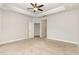 Primary bedroom featuring neutral carpet, tray ceiling, a ceiling fan, and two doorways at 1217 Linkwood Way, Fuquay Varina, NC 27526