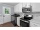 Well-lit kitchen area featuring stainless steel appliances, white cabinetry, and marble countertops and washer/dryer combo at 1615 Malta Ave, Raleigh, NC 27610