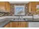 Kitchen sink with stainless fixtures, wood cabinets, stone-look countertops, and colorful tile backsplash at 162 E Abbey Ct, Smithfield, NC 27577