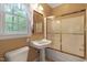 Bathroom featuring a pedestal sink, a frosted sliding glass shower door, and a window to the outside at 2004 Riverview Dr, Clayton, NC 27527