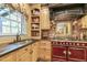 Close up of kitchen with custom cabinets, red range, and black countertop at 2004 Riverview Dr, Clayton, NC 27527