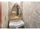 Elegant powder room featuring patterned wallpaper, a gold-framed mirror, and a pedestal sink at 2004 Riverview Dr, Clayton, NC 27527
