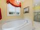 Bathroom featuring a standalone tub with marble surround, chandelier, and large window at 21 Kimberly Dr, Durham, NC 27707