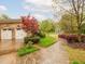 Long driveway leading to the brick home with manicured landscaping and a red maple tree at 21 Kimberly Dr, Durham, NC 27707