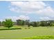 Golf course green with manicured lawn, scattered trees, course clock, and benches for relaxation at 21 Kimberly Dr, Durham, NC 27707
