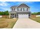 Charming two-story home features a gray facade, inviting front porch, and a two-car garage at 211 Tobacco Barn Dr, Angier, NC 27501