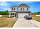 Charming two-story home features a gray facade, inviting front porch, and a two-car garage at 211 Tobacco Barn Dr, Angier, NC 27501