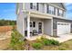 Inviting front porch with seating, leading to a charming gray two-story home with a two-car garage at 211 Tobacco Barn Dr, Angier, NC 27501