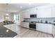 Modern kitchen boasts stainless steel appliances, gray backsplash, granite countertops, and an adjacent dining area at 215 Kipling Creek Dr, Fuquay Varina, NC 27526