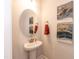 Stylish powder room showcasing a pedestal sink, round mirror, and attractive wall art at 215 Kipling Creek Dr, Fuquay Varina, NC 27526