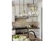 Close-up shot of a kitchen with decorative hanging lights above a granite countertop and stainless steel stove at 2408 Merion Creek Dr, Apex, NC 27539