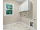 Functional laundry room with built-in cabinets, tile flooring, and a bright window at 303 Cherrybirch Ln, Zebulon, NC 27597