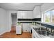 Bright kitchen featuring white cabinets, stainless steel sink, and wood flooring with a view into the living room at 312 E Highland Ave, Rocky Mount, NC 27801