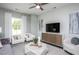 Cozy living room with modern furniture, a ceiling fan, and a decorative console underneath the wall mounted television at 355 Fosterton Cottage Way, Raleigh, NC 27603