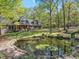 Charming brick home featuring a pond with lily pads, lush greenery, and mature trees surrounding the property at 363 Dublin Dr, Sanford, NC 27330