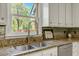 Kitchen counter featuring a sink, granite countertops, tile backsplash, and white cabinets at 363 Dublin Dr, Sanford, NC 27330