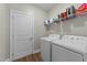 Functional laundry room with modern washer and dryer, white cabinets, and convenient shelving at 396 Martins Mill Ct, Wendell, NC 27591
