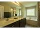 Bright bathroom featuring a double vanity, large mirror, and separate tub at 40 Patricia S Vann Ct, Dunn, NC 28334