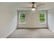 Bright bedroom with carpet floors, ceiling fan, and view to the backyard through two windows at 400 Collington Dr, Mebane, NC 27302