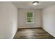 Empty bedroom featuring light wood floors, white walls and trim, and a window with a tree view at 400 Collington Dr, Mebane, NC 27302