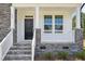 Close-up of a charming front porch with stone accents, a black front door, and white railings at 420 Shelby Meadow Ln, Angier, NC 27501