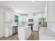 Modern kitchen featuring white cabinets, stainless steel appliances, an island with a quartz countertop, and light wood floors at 420 Shelby Meadow Ln, Angier, NC 27501
