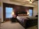 Spacious main bedroom with a dark wood bed frame, tray ceiling, and two windows at 4610 Miller Dr, Durham, NC 27704