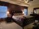 Spacious main bedroom with a dark wood bed frame, tray ceiling, and two windows at 4610 Miller Dr, Durham, NC 27704