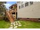 Backyard with a staircase leading to an upper deck, a manicured lawn and brick accents at 4709 Knights Arm Dr, Durham, NC 27707