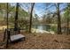 Picturesque pond surrounded by mature trees with a bench nearby at 4709 Knights Arm Dr, Durham, NC 27707