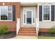 Close up of home entrance featuring a brick staircase and white railings, and a storm door at 4905 Homestead Dr, Mebane, NC 27302