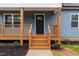 Welcoming front porch with wooden railings, steps and a modern black front door at 508 N Charles St, Mebane, NC 27302
