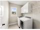 Well-lit laundry room with washer, dryer, white cabinets and a window to the outside at 52 Sagebrook Ct, Zebulon, NC 27597
