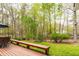 A spacious backyard with a deck, bench, and mature trees provides a serene outdoor space at 706 Kensington Dr, Chapel Hill, NC 27514