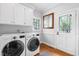 Clean laundry room with modern washer and dryer, white cabinets, and hardwood floors at 706 Kensington Dr, Chapel Hill, NC 27514
