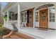 Brick home exterior with covered front porch featuring white columns, lion statue and wooden front door at 7336 Barham Hollow Dr, Wake Forest, NC 27587