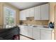 Bright laundry room featuring white cabinetry, a utility sink, and natural light from a large window at 7336 Barham Hollow Dr, Wake Forest, NC 27587