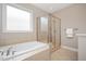 A bathroom with a soaking tub, glass-enclosed shower, tile floors, and a window at 800 Laurel Garden Way, Cary, NC 27513