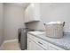Well-equipped laundry room with modern washer, sink, granite countertop, and ample cabinet space at 800 Laurel Garden Way, Cary, NC 27513