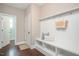 A mudroom with a built-in bench, storage shelves, coat hooks, and a white door at 800 Laurel Garden Way, Cary, NC 27513