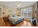 Bright bedroom with a ceiling fan, a large window, hardwood floors, and cozy blue bedding at 8308 Buck Crossing Dr, Durham, NC 27713