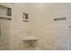 Tiled shower featuring a built-in seat and storage shelves with pebble flooring at 8308 Buck Crossing Dr, Durham, NC 27713