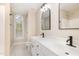 A stylish bathroom with double sinks, modern fixtures, white cabinetry, arched mirror, and a tiled shower at 9332 Carley Cir, Garner, NC 27529