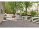 Spacious back deck with gray tiles and a white railing surrounded by lush trees and a white fence at 1008 Double Spring Ct, Apex, NC 27502